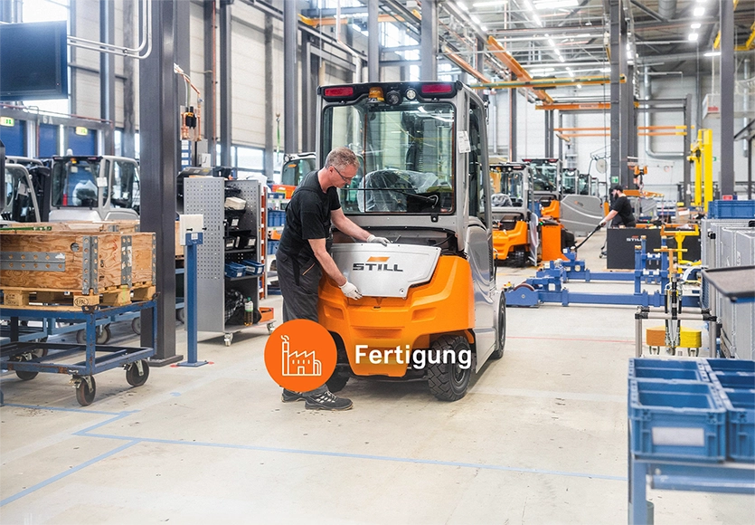 Ein Mitarbeiter montiert in einer Produktionshalle ein Teil am Heck eines orange-grauen STILL Gabelstaplers, dazu der Schriftzug „Fertigung“.