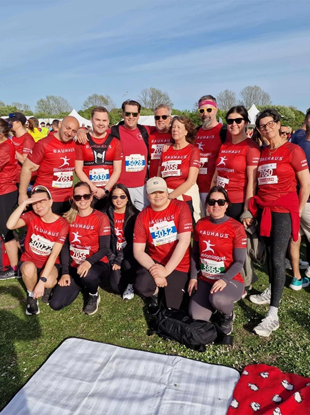 Gruppenfoto eines Laufteams in roten Shirts mit Startnummern auf einer Wiese.