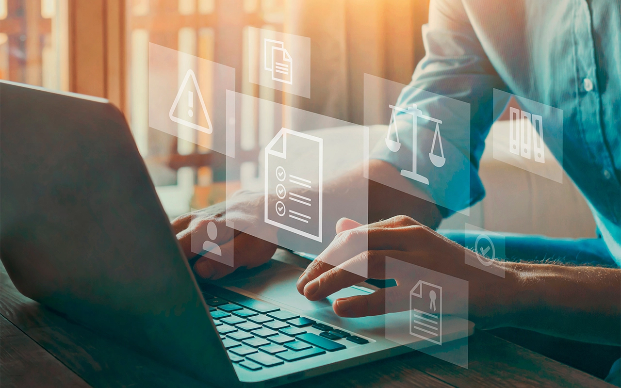 A person working on a laptop, with floating icons for documents, a checklist, a warning sign, scales of justice and a certificate.