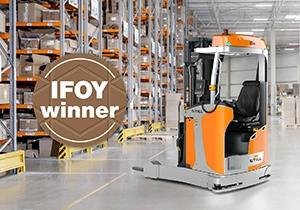 An orange and grey STILL reach truck in a warehouse aisle with tall racks, with an “IFOY winner” badge.