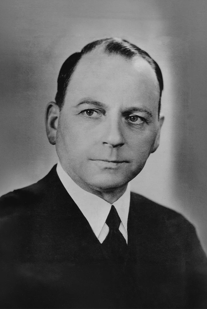 Historical black-and-white portrait of a man in a dark suit, white shirt and tie.